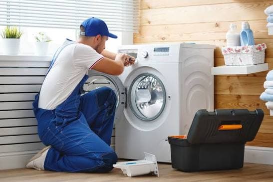 Technician repairing a front-load washing machine in a home